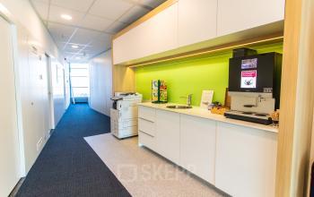 Bright office space for rent at Avenue Ceramique 221, Maastricht featuring a well-equipped pantry area with a coffee machine and printer nearby.
