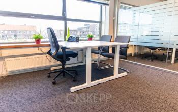 Furnished office space with two chairs and a desk, featuring large windows and a glass partition, available for rent at Avenue Ceramique 221, Maastricht.