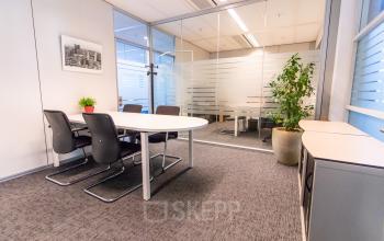 Modern office space for rent on Avenue Ceramique 221 in Maastricht, featuring a conference table and chairs, with plants adding a touch of greenery.
