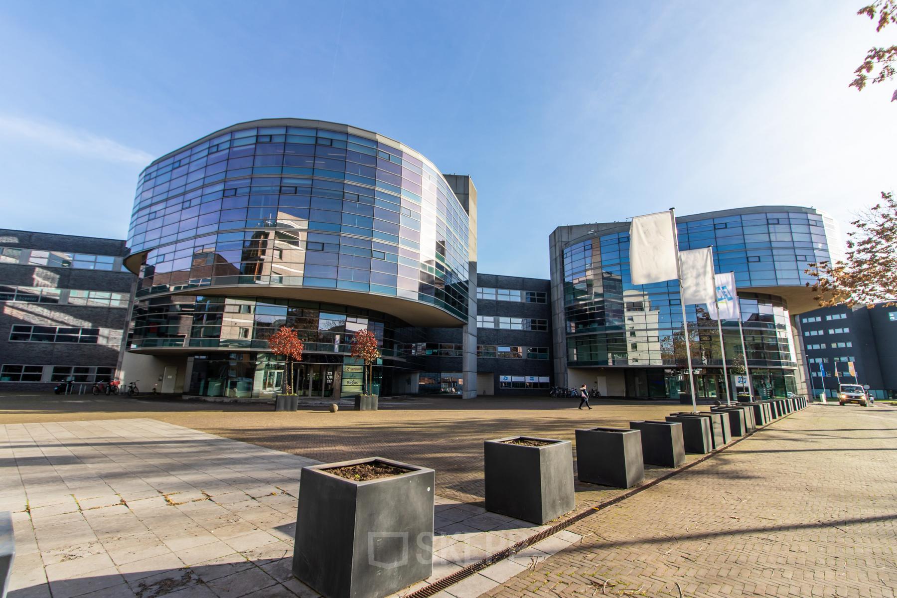 Modern office building at Avenue Ceramique 221, Maastricht, available for office space rental, featuring glass facades and spacious outdoor areas.