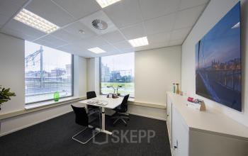 Modern office space rental at Stationsplein 8K, Maastricht, featuring a tidy desk setup with a view of the outdoors.