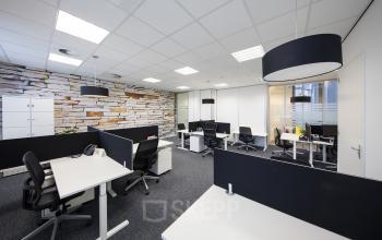 Modern Maastricht office space rental at Stationsplein 8K with well-lit workstations and stylish stone accent wall.