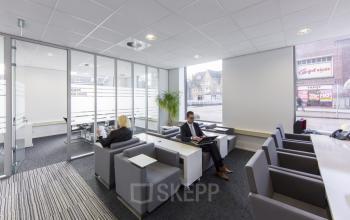 Modern and well-lit office space rental at Stationsplein 8K, Maastricht, with individuals engaged in business activities.