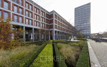 Exterior view of office building at Stationsplein 8K, Maastricht, with a manicured garden and modern architectural design, ideal for office space rental.