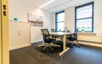Bright and furnished office space at Robert Schumandomein 2, Maastricht, ideal for office space rental. It features a desk for collaborative work and large windows providing natural light.