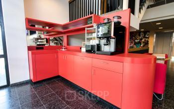 Vibrant red pantry area in the office to rent at Boschstraat 21, Maastricht, with a coffee machine and modern amenities.