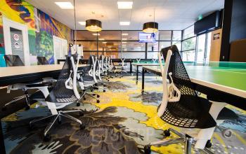 Modern office space rental at Boschstraat 21, Maastricht, featuring contemporary workstations, vibrant decor, and ample seating.