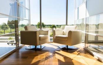 Bright office space with two modern chairs and large window view at Brieltjenspolder 28, Made, ideal for office space rental.