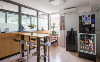 Espace de bureau à louer accueillant avec comptoir en bois, chaises hautes et distributeurs à Avenue du Prado 24, Marseille 8ème.