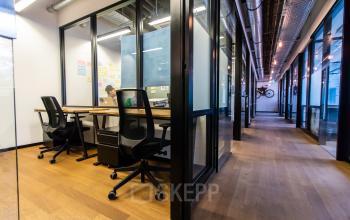 Modernes Büro im Viktualienmarkt 8, München Altstadt mit Glaswänden und ergonomischen Stühlen. Ideal, um Büroraum zu mieten. Eine Person arbeitet konzentriert am Schreibtisch.