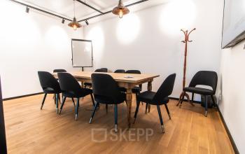 A well-lit office space for rent in Munich Old Town with a large wooden table surrounded by chairs, suitable for meetings or conferences.