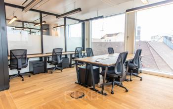Modern office space for rent at Herzogspitalstraße 24, Munich Old Town, featuring large windows and ergonomic chairs around wooden desks.