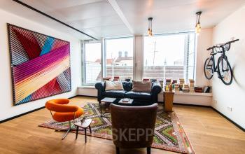 Furnished office space in Munich Old Town with colorful decor, sofas, and a bicycle mounted on the wall, available for rent.