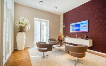 Lounge-Bereich im Büro Maximilianstraße 2, München Altstadt mit moderner Einrichtung, Sesseln und Wandfernseher.