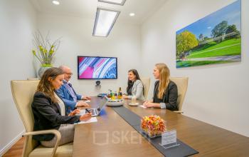 Geschäftstreffen in einem modernen Konferenzraum im Büro in der Maximilianstraße 2, München Altstadt, München. Vier Personen besprechen an einem Tisch. Ideal um Bürofläche zu mieten.
