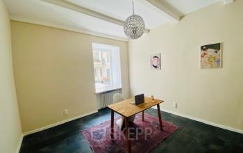 Helles Büro im Gebäude Thierschstr 33, München Altstadt, das einen minimalistisch eingerichteten Arbeitsbereich mit einem Holztisch, Stuhl und Laptop zeigt.