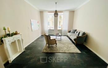 Büro in Thierschstr 33, München Altstadt mit stilvoller Möblierung, inklusive Sofa und Stühlen, großem Fenster und dekorativem Kamin.