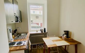 Bürofläche mieten in der Thierschstr 33, München Altstadt: Ein heller, möblierter Raum mit Tisch, Stühlen und Küchenzeile.