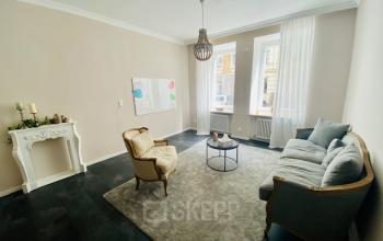 Eleganter Büroraum zur Miete in München Altstadt, Thierschstr 33 mit stilvoller Einrichtung inklusive Sofa, Sessel und Teppich in einem hellen Raum mit großen Fenstern.