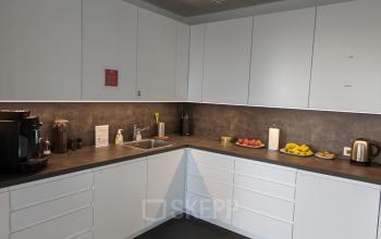 Modern pantry with white cabinets and countertops, fully stocked with kitchen appliances and various fruits.
