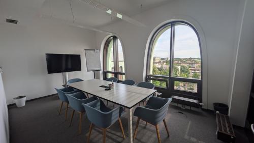 Büroraum mieten in Christoph-Rapparini-Bogen 25, München Laim, ausgestattet mit Konferenztisch und blauen Stühlen, großem Fenster mit Blick nach draußen.