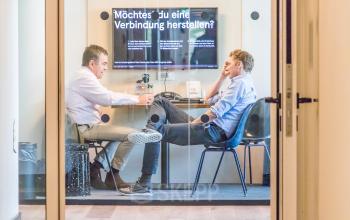 Zwei Männer in geschäftlicher Besprechung in einem möblierten Konferenzraum am Oskar-von-Miller-Ring 20, München Maxvorstadt. Bürofläche mieten für produktive Meetings.