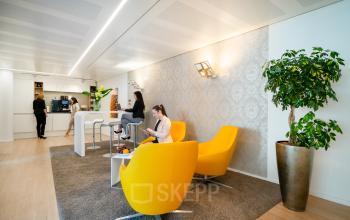 Bright office space rental at Theresienstraße 1, Munich Maxvorstadt, featuring modern furnishings, relaxed seating, and a coffee bar area where professionals are working and socializing.