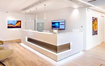 Modern reception area in Theresienstraße 1, Munich Maxvorstadt, featuring a sleek white desk, wall art, and beige seating. Ideal for office space rental.