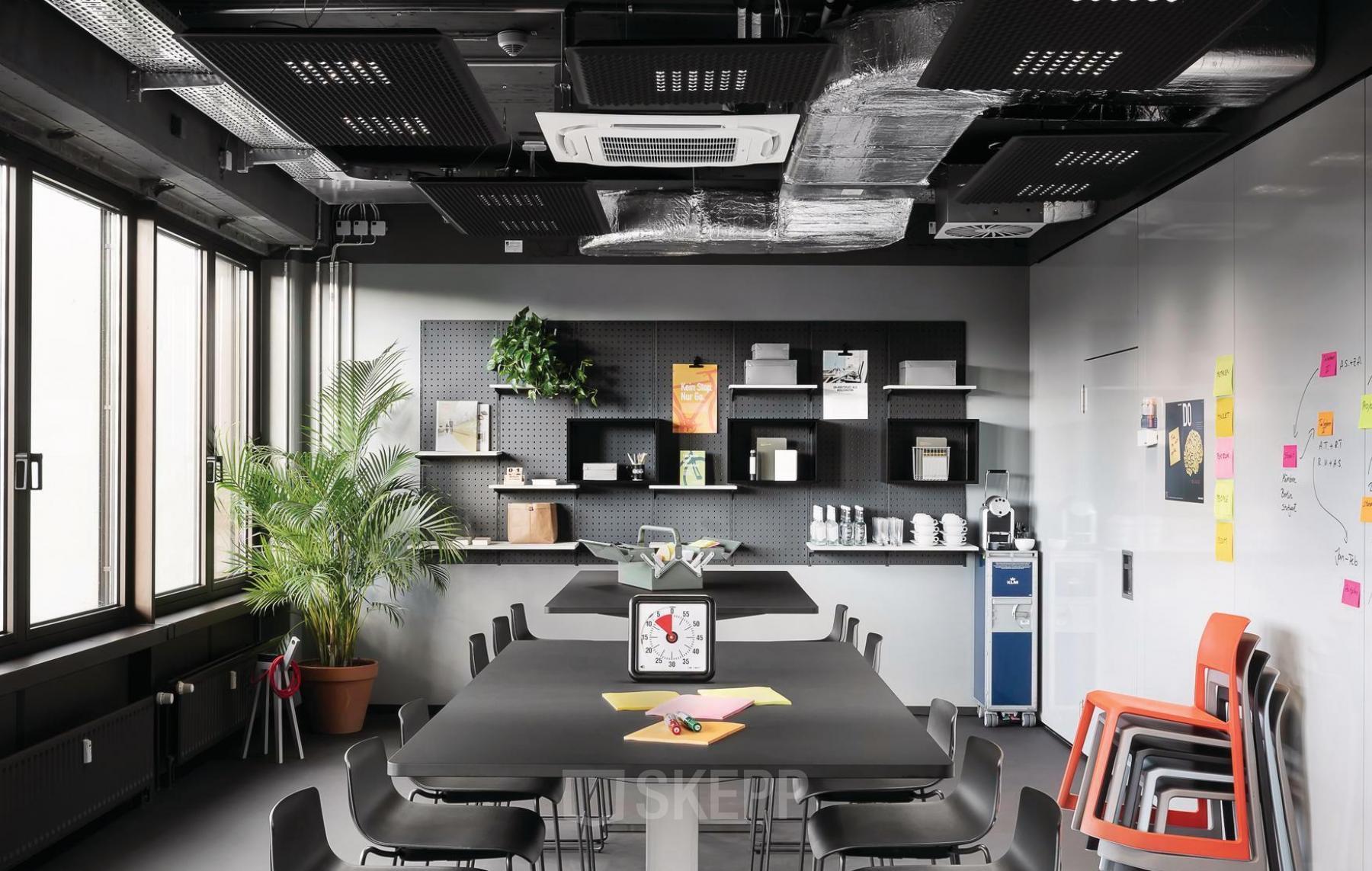 Moderner Büroraum in der Brienner Straße 45 a-d, München Maxvorstadt, mit langer schwarzer Tischreihe, schwarzen Stühlen und Regalen an der Wand. Ideal zum Büroraum mieten.