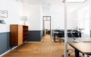 Bürofläche mieten in der Seidlstraße 5, München Maxvorstadt. Moderner Raum mit Holzboden, Bücherregal und mehreren Schreibtischen mit Lampen, ohne Personen.