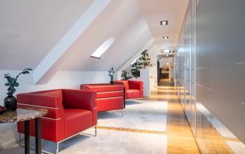 Moderne und stilvolle Bürofläche mieten in München Maxvorstadt, Ludwigstraße 8. Hell mit roten Sesseln, Pflanzen und eleganter Beleuchtung.