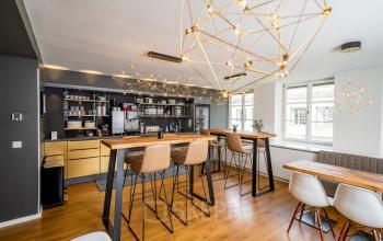 Moderner Büroraum in der Ludwigstraße 8, München Maxvorstadt, mit stilvoller Möblierung, hohen Tischen und eleganter Beleuchtung. Perfekt um einen Büroraum zu mieten und effizient zu arbeiten.