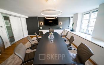 Moderner Konferenzraum in München Maxvorstadt, ausgestattet mit großem Tisch und eleganter Beleuchtung, ideal für Teams, die eine Bürofläche mieten möchten.