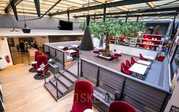 Modernes Büro in der Hopfenstraße 8, München Maxvorstadt, mit offenen Arbeitsbereichen, roten Sitzmöglichkeiten und großen Fenstern, ideal zum Büroraum mieten.