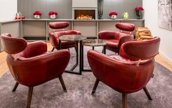 Gemütlicher Lounge-Bereich in der Hopfenstraße 8 in München Maxvorstadt, ideal um Büroraum zu mieten, mit roten Sesseln und Kamin für angenehme Meetings.