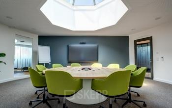 Konferenzraum mit grünen Stühlen und großem Holztisch im Bürogebäude Carl-Zeiss-Ring 15a, München Nord. Bürofläche mieten in modernem Ambiente.