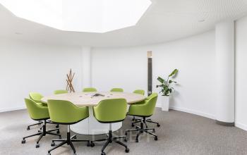 Modernes Büro zur Miete am Carl-Zeiss-Ring 15a, München Nord, mit ovalem Konferenztisch und grünen Stühlen.