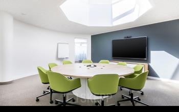 Moderner Konferenzraum im Büro Carl-Zeiss-Ring 15a, München Nord, mit großem runden Tisch und grünen Stühlen, ideal für Konferenzen.