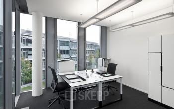 Modernes Büro in München Schwabing in der Mies-van-der-Rohe-Straße 8 mit zwei Arbeitsplätzen, großen Fenstern und minimalistischer Einrichtung.