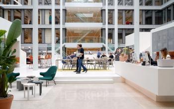 Modernes, lichtdurchflutetes Büro im München Werksviertel an der Mühldorgstraße 8 mit offenen Arbeitsbereichen, in denen Menschen geschäftliche Besprechungen und Arbeiten durchführen. Ideal für Firmen, die ein Büro mieten möchten.