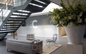 Modern office reception area at Rijksweg 79 in Naarden, featuring stylish seating, a large staircase, and a welcoming atmosphere.