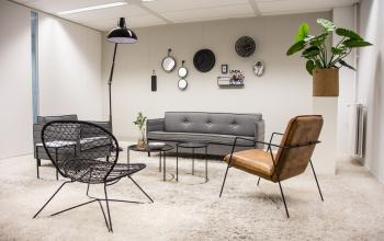Modern furnished office lounge with stylish seating, wall decor, and plants at Rijksweg 79, Naarden, office space rental available.