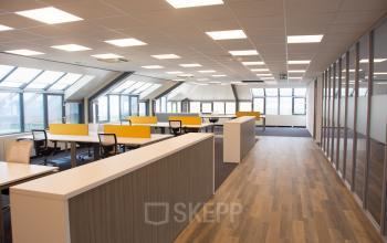 Bright office space with large windows, modern workstations, and yellow dividers at Rijksweg 79, Naarden, available for office space rental.