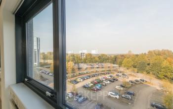 View from an office at Nevelgaarde 8-19, Nieuwegein, showcasing a parking lot surrounded by greenery, ideal for office space rental.