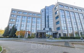 Modern office building at Nevelgaarde 8-19 in Nieuwegein, featuring a reflective glass facade with multiple levels, set within a serene urban environment. Ideal for those seeking office space rental in Nieuwegein.