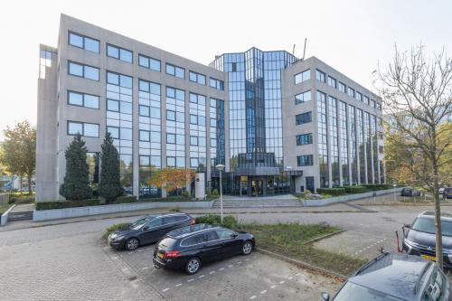 Exterior view of office building at Nevelgaarde 8-19, Nieuwegein, featuring modern glass façade and ample parking. Ideal location for office space rental.