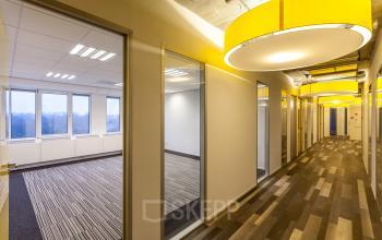 Bright corridor with modern lighting at Zoomstede 13-25 in Nieuwegein, leading to glass-enclosed office workspaces.