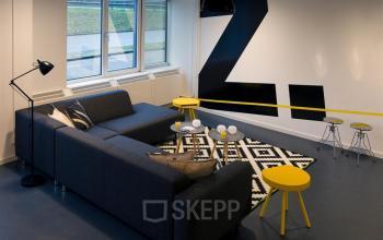 Modern lounge area in an office at Zoomstede 13-25, Nieuwegein, with cozy seating and yellow accents.