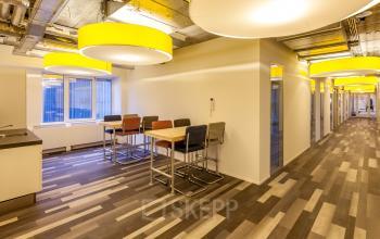 Modern office kitchen area at Zoomstede 13-25, Nieuwegein, with bar seating and bright yellow ceiling lights, ideal for office space rental.
