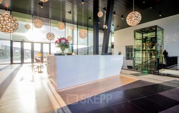Spacious and modern reception area at Jonkerbosplein 52, Nijmegen, ideal for office space rental. Features unique lighting and a sleek desk, perfect for welcoming visitors.